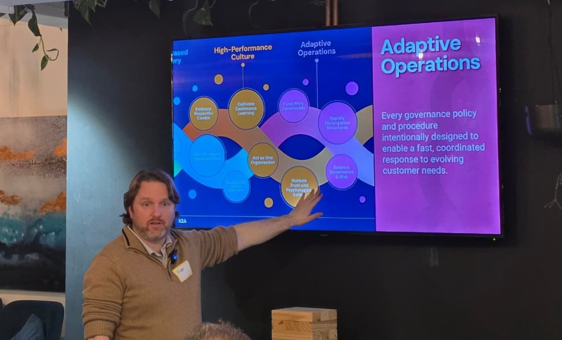 Evan Leybourn presenting the Adaptive Operations domain slide: governance designed for fast, coordinated response to evolving customer needs, with Fund Work Dynamically, Rapidly (Re)organize Structures, and Balance Governance & Risk